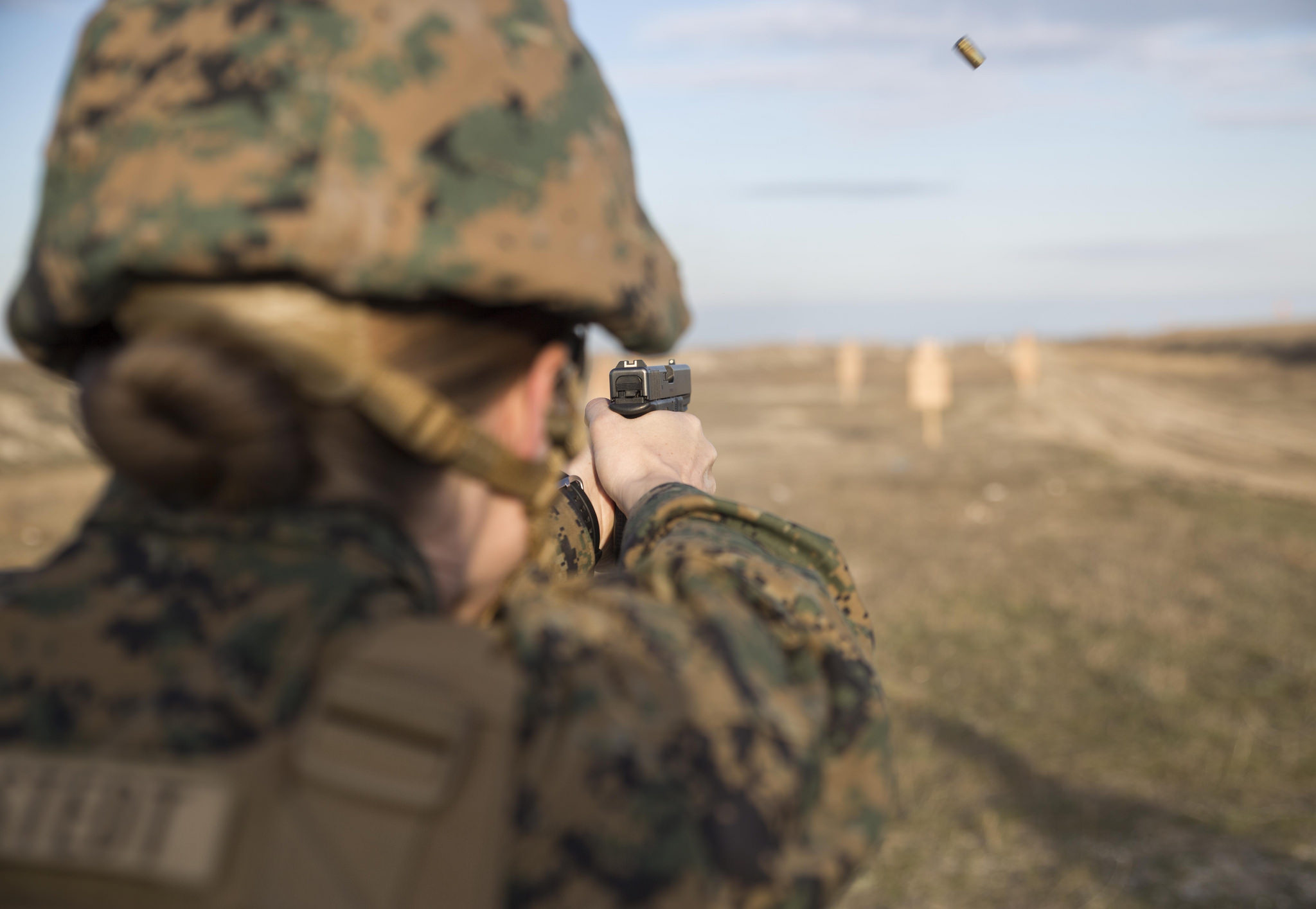 "A U.S. Marine, assigned to the 24th Marine Expeditionary Unit (MEU), Female Engagement Team, fires a Romanian troop’s pistol during a live-fire exercise at Capu Midia training grounds in Romania." 