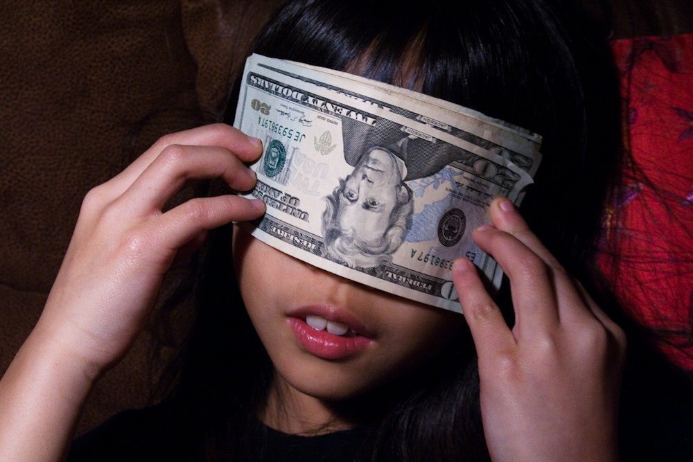 Girl Covering Her Eyes with a Stack of $20 Bills