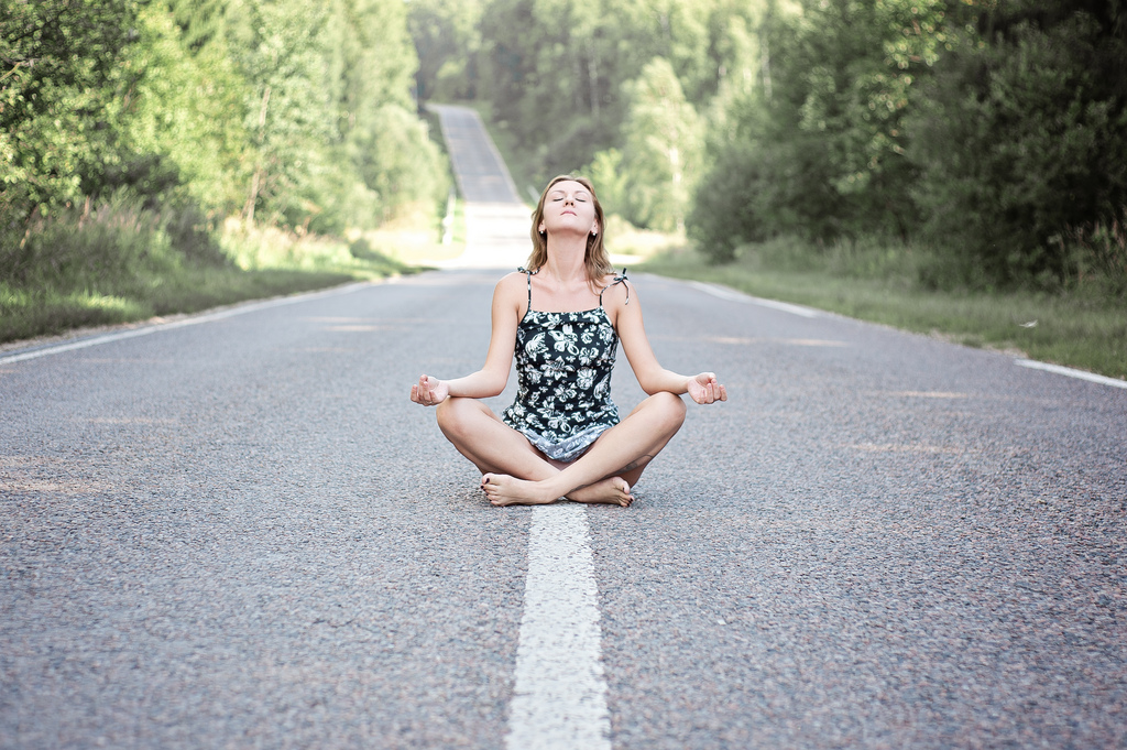 girl doing meditation pose in middle of the road