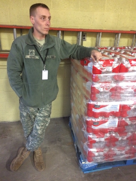 Corporal Jack King leans against a pallet of water bottles in Flint, Mich.