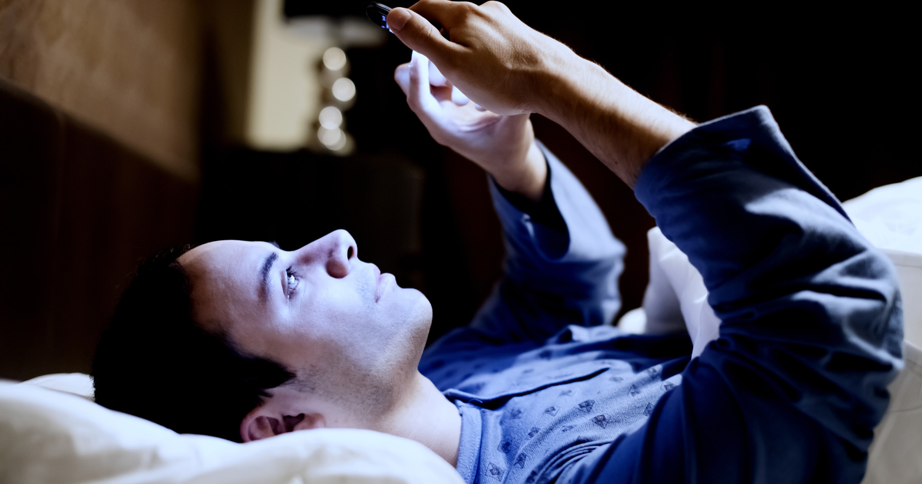 Picture of a guy using his phone before he goes to sleep