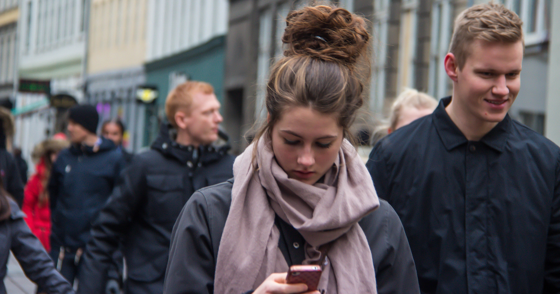 Young woman in a crowd checking her phone