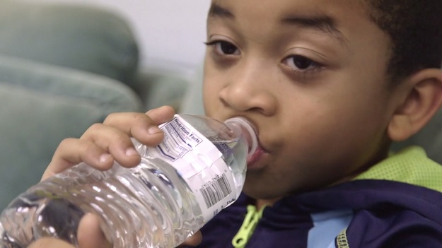 Young Flint resident drinking bottled water.