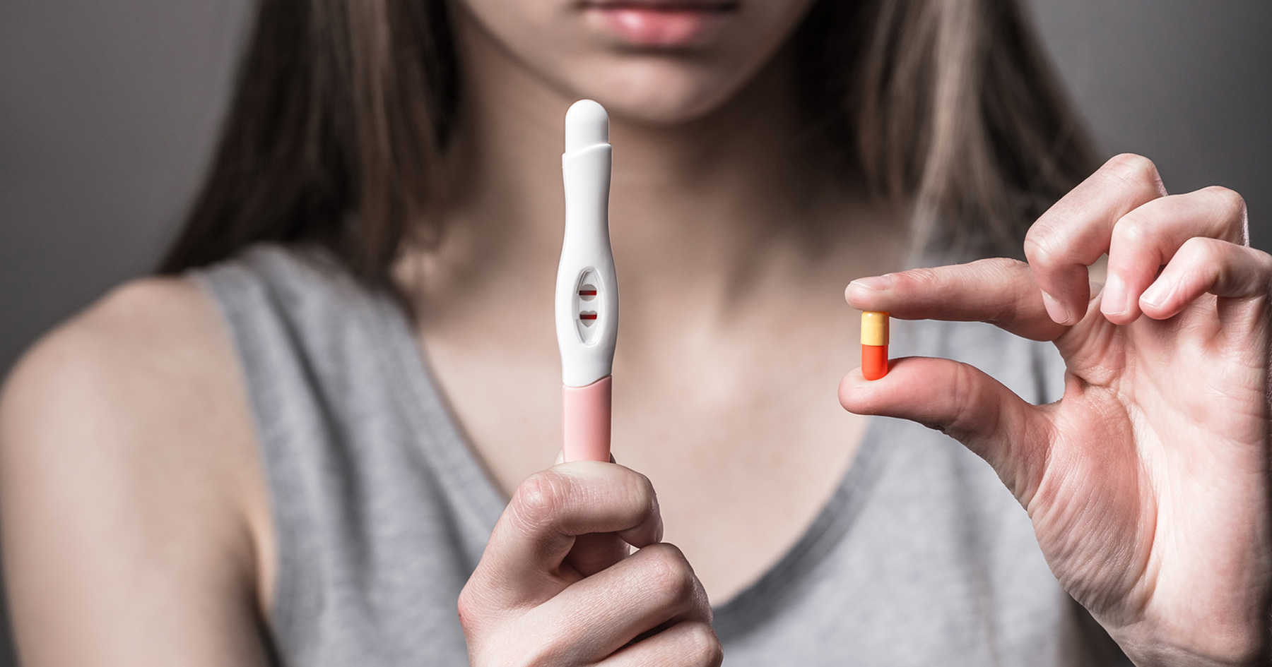 woman-holding-pregnancy-test-and-pills
